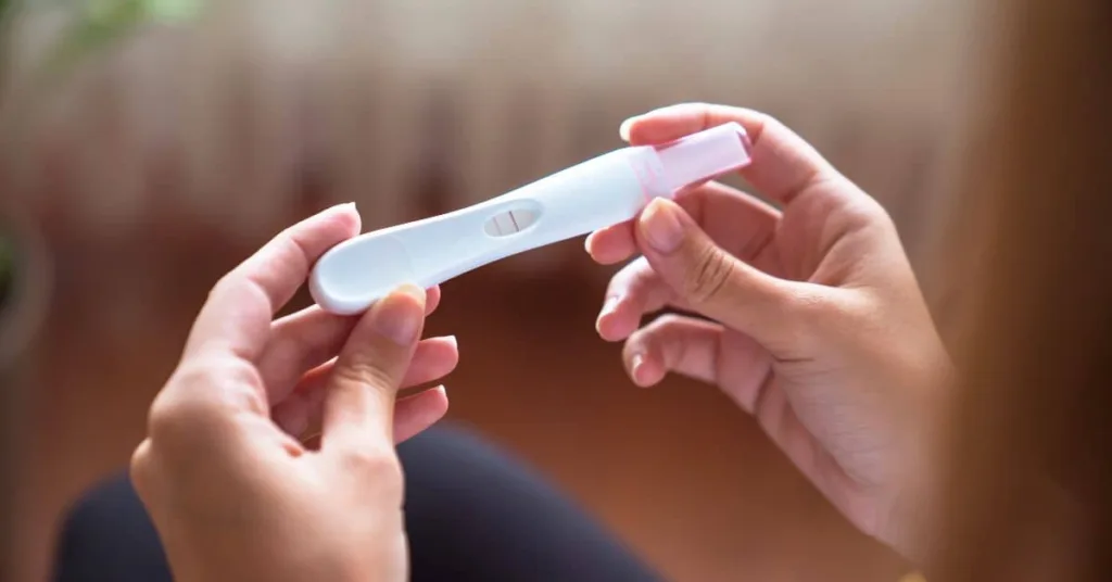 Woman holding pregnancy test, looking at results with happy expression